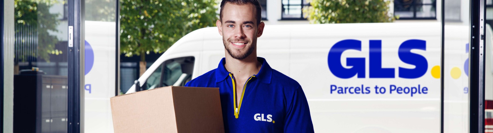 A delivery man holds a parcel in front of his van