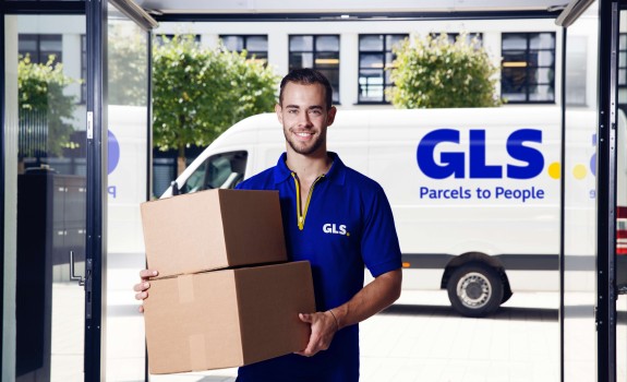 A delivery man holds a parcel in front of his van