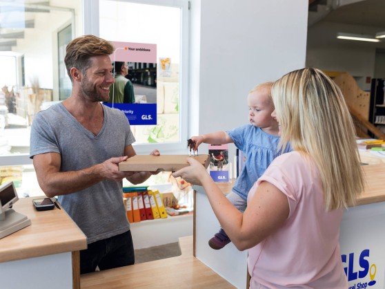Mujer con un bebé en brazos devuelve un paquete en un Parcel Shop