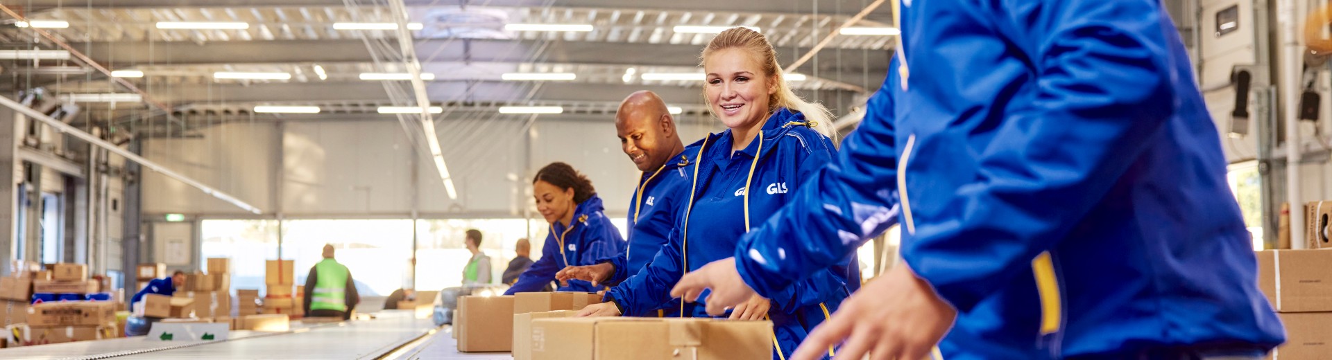 GLS työntekijät pakettilinjaston äärellä tekemässä yhteistyötä