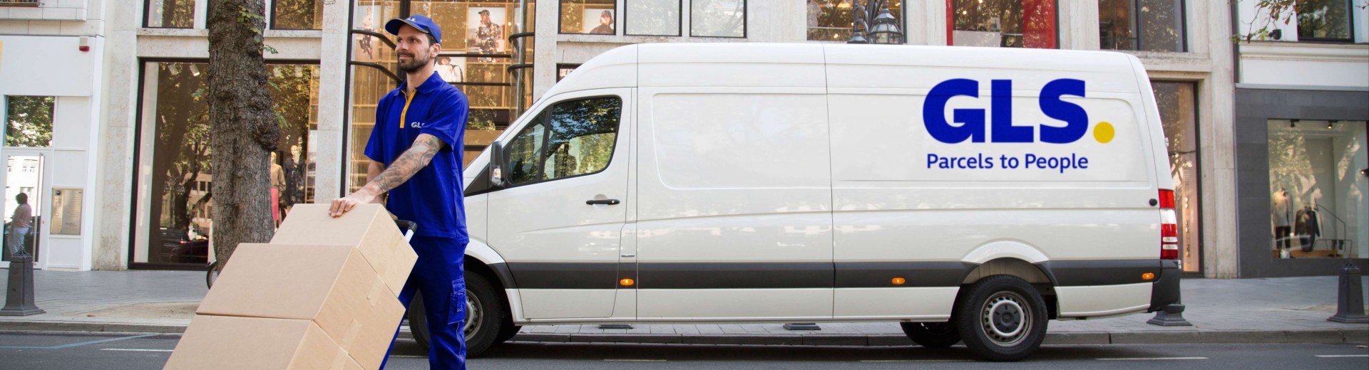 Delivery man carries parcels in front of his van