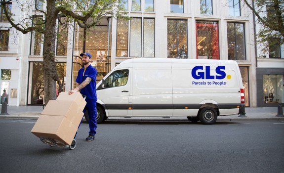 Delivery man carries parcels in front of his van