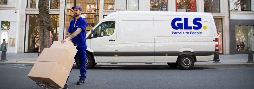 Delivery man carries parcels in front of his van