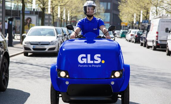 A courier on an e-scooter delivers parcels to customers.