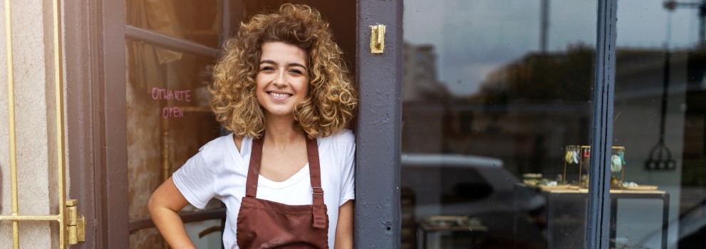 female shop owner smiling in front of her shop