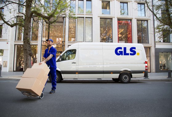 GLS kurir s paketi in GLS kombijem v ozadju