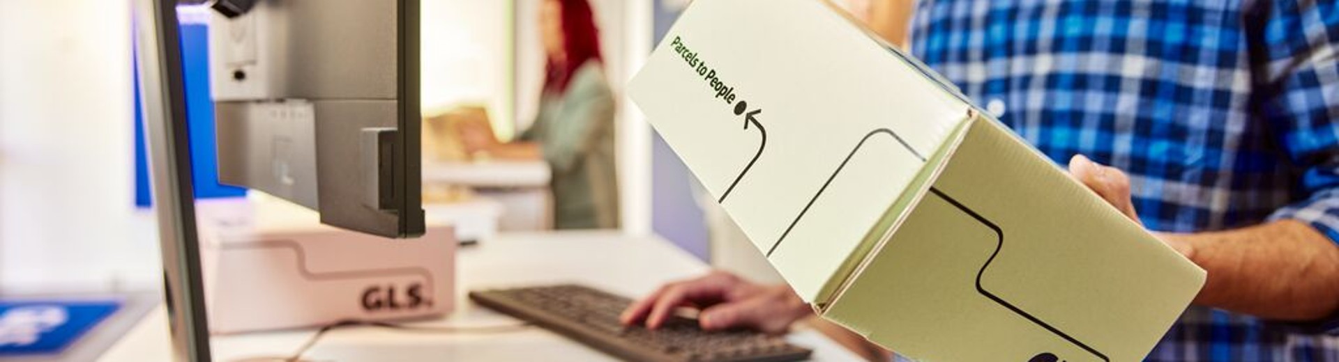 Zaposleni v GLS pripravlja paket v fulfillment centru