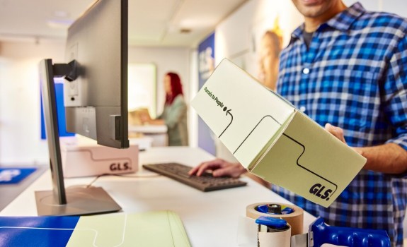 Zaposleni v GLS pripravlja paket v fulfillment centru